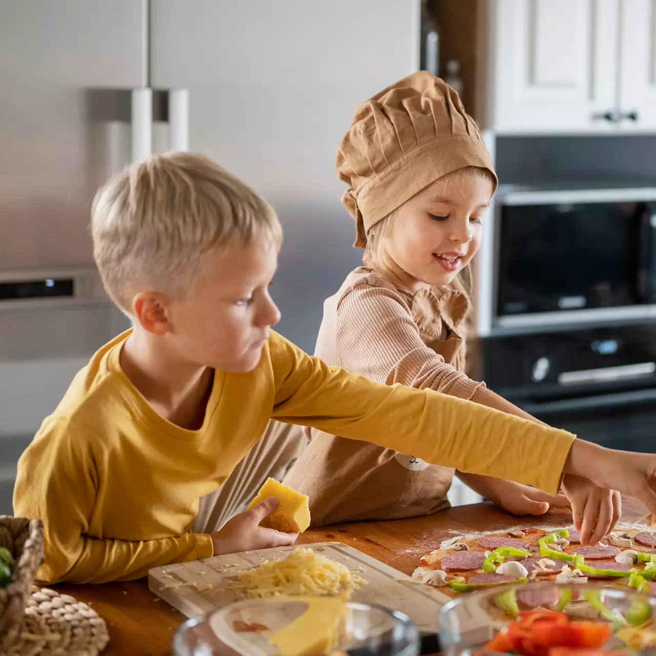 Un garçon et une fille en toque de chef préparant une pizza